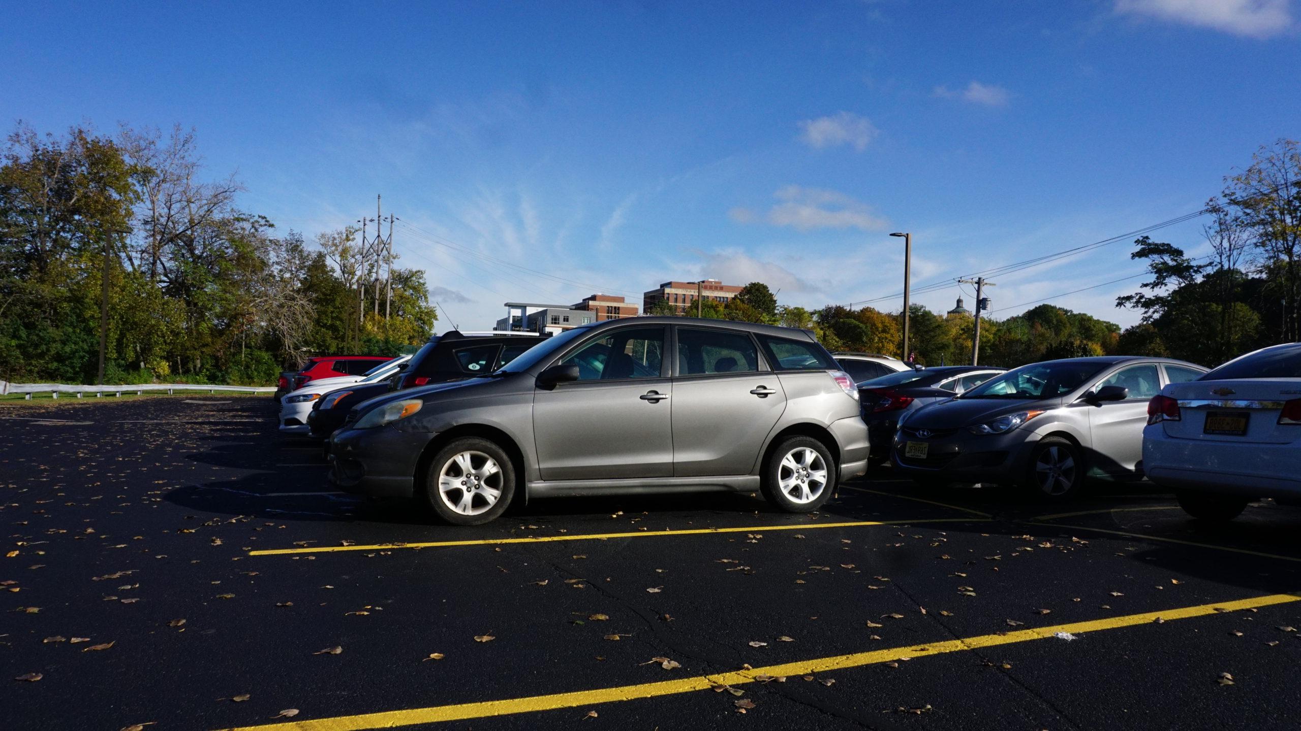 车辆s parked in University of Rochester lot with brick buildings in background